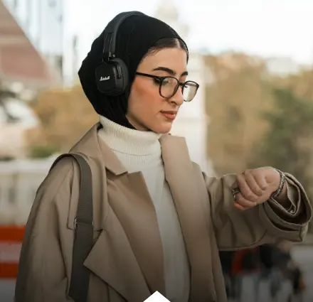 فتاة تستخدم سماعة الرأس وتنظر إلى الساعة